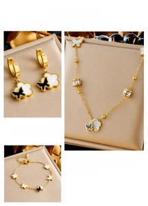 Detail view of gold stainless steel jewelry set featuring butterfly and floral charms