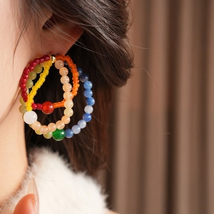 Detail view of colorful beaded multi-layer hoop earrings on a model showing vintage style