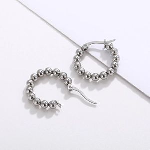 Vue macro de boucles d'oreilles minimalistes en acier argenté en U avec perles sur fond blanc