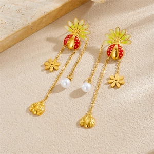 Gold plated ladybug and flower tassel earrings with white pearls on a textured stone base