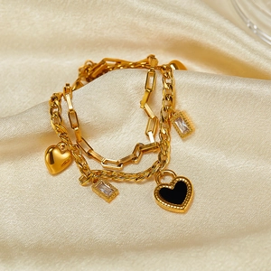 Detail of double-layer gold heart bracelet with black enamel charm and cubic zirconia stones