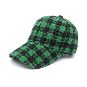 Dettaglio ravvicinato del tessuto tweed a quadri verde scuro e nero di un berretto