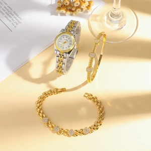 Schmuckset aus silber-goldener Stahluhr und Kristallarmbändern auf warmem Hintergrund