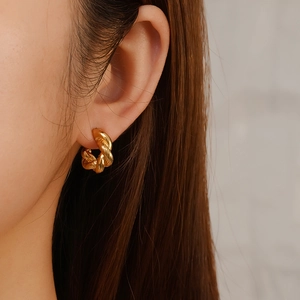 Irregular twisted gold hoop earrings made of 18K plated stainless steel on female model