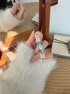 Detailed shot of retro oval watch dial with elegant double-row pearl strap on wrist