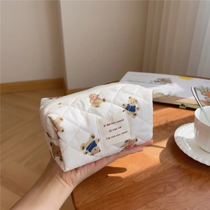 Detail of white quilted cotton makeup bag with bear patterns and French woven label