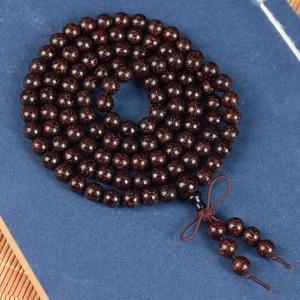 Macro detail of 108 blood sandalwood beads featuring gold flecks and a Chinese knot tassel