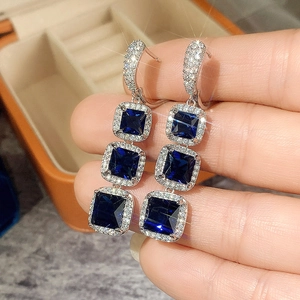 Detail of tiered square blue zircon earrings with silver hooks and micro-pave accents