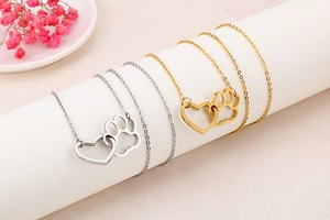 Close-up of gold and silver heart-shaped cat paw pendant necklaces on display props
