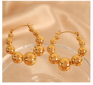 Macro shot of polished gold bubble hoop earrings featuring geometric spherical beads