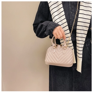 Close-up of nude pink shell bag with glossy finish and elegant gold chain strap