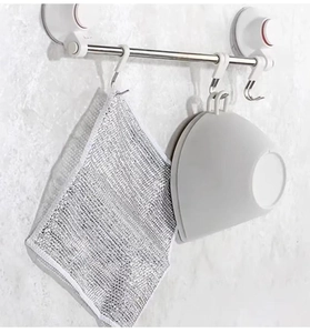 Close-up of a silver wire dishcloth and grey silicone brush hanging on a suction cup rack