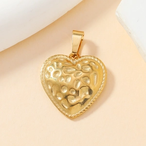 Detail view of golden heart pendant featuring unique hammered texture and beaded edges