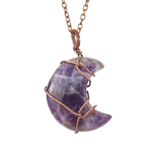 Macro shot of handmade wire-wrapped crescent moon amethyst pendant on vintage chain