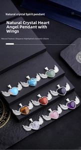Macro shot of heart-shaped crystal pendants with silver metal wings on a black display