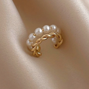 Dettaglio del ear cuff dorato a doppio strato con perle bianche su pregiato tessuto in seta