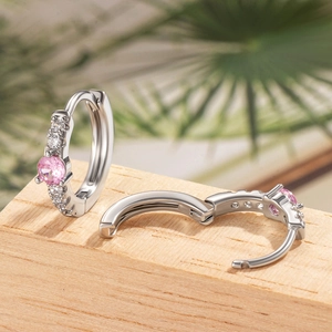 Silver hoop earrings with pink zircon and clear crystals on a minimalist wooden background