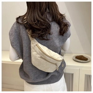 Detail of off-white corduroy crossbody waist bag shown on model in a casual setting