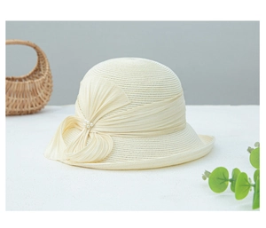 Détail d'un chapeau de paille crème avec un nœud plissé élégant et des perles blanches