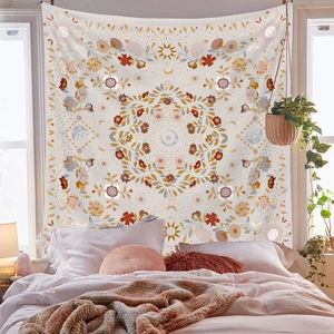 Detail of bohemian mandala tapestry with sun and moon motifs hanging above a bedroom bed