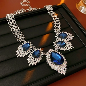 Detail of luxury necklace with blue water-drop gems and sparkling rhinestones on black tray