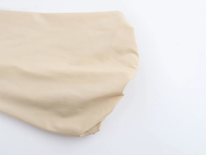 Gros plan du tissu beige de robe de vacances montrant la texture lisse et le drapé naturel