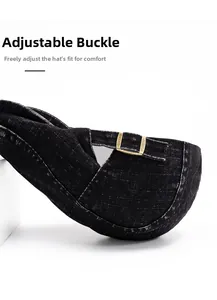 Detailed macro view of the adjustable bronze metal buckle on black denim beret hat