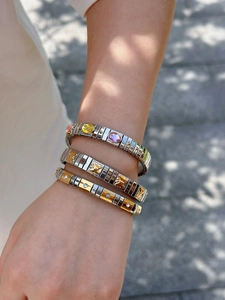 Detailed view of layered stainless steel stretch bracelets with butterfly and crystal motifs