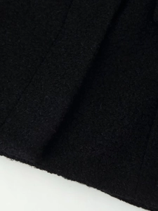 Close-up of high-quality black wool fabric showing detailed texture and fiber weave