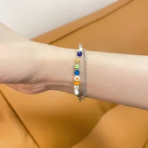 Detalle de pulsera de doble capa con cuentas de flores de colores y cadena ajustable