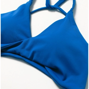 Close-up of bright blue yoga sports bra featuring a criss-cross ruched design on the chest