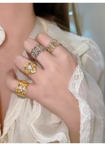 Détail de quatre bagues fleurs plaquées or et argent avec zircons sur les doigts