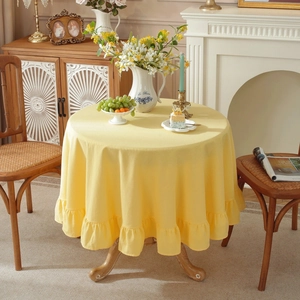 Close-up of a yellow linen tablecloth with ruffled edges on a round dining table