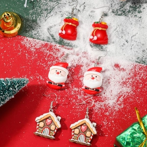 Detailed view of Christmas earrings with Santa Claus, gift bags and gingerbread house charms