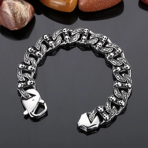Close-up of punk style stainless steel Cuban chain bracelet with detailed skull patterns