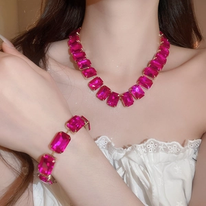 Close-up of luxury gold necklace and bracelet set with square rose red gemstones