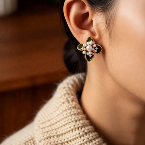 Gros plan de boucles d'oreilles fleur vintage en émail vert et perle sur modèle