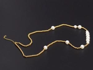Detailed macro view of trendy titanium steel necklace with gold beads and white pearls
