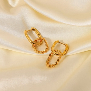 Detailed view of gold twisted pendant earrings on premium champagne silk background