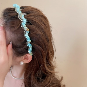 Close-up of wavy acrylic headband with irregular light blue stones on a model