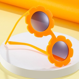 Orange sunflower shaped kids sunglasses with dark round lenses on white display stand