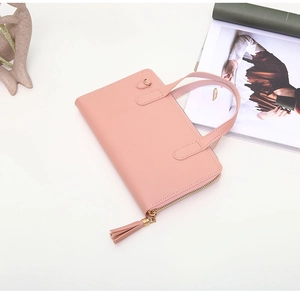 Detail of pink leather handbag with gold zipper, fringe tassel, and sturdy dual handles