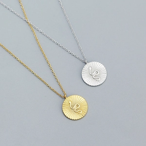 Macro detail of gold and silver round pendants with engraved snake design and radial texture