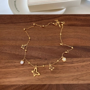 Detail view of gold butterfly pendant with pearl and S925 silver stamp on jewelry tray