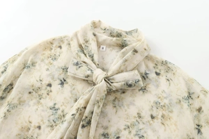 Détail du col d'une chemise en mousseline fleurie avec nœud élégant et étiquette S