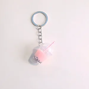 Close-up of a pink bubble tea keychain with realistic black pearls and striped straw