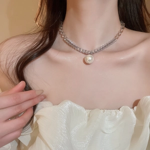 Close-up of elegant beaded necklace with gray faceted beads and white pearl pendant on model