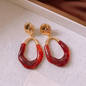 Vintage gold metal earrings with red marble resin rings on a textured fabric backdrop