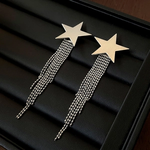 Macro d'oreilles pendantes en étoile argentée avec franges sur plateau en velours noir