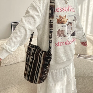 Close-up of plush shoulder bag with brown geometric stripes and soft textured fabric